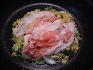 生地を混ぜて豚肉をのせ焼く写真