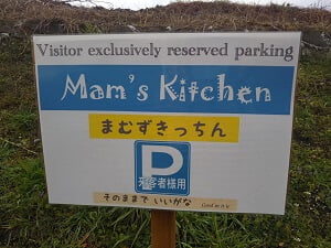 裏の道路沿いにある駐車場案内の立て看板の写真