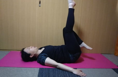 仰向けで足を上げ踵でお尻を叩く写真