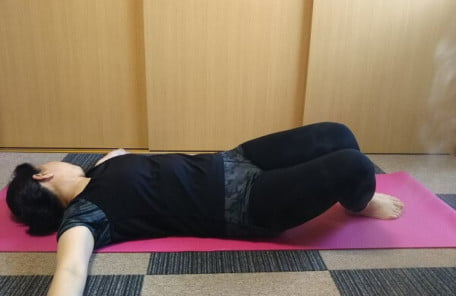 両手を開き、立てた膝と反対側に頭を傾けるストレッチの写真