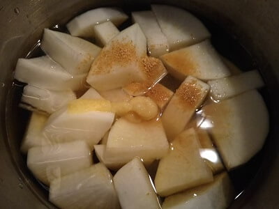 鍋に大根と調味料を入れてにる社員