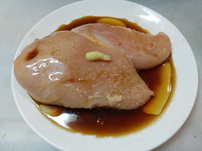 鶏むね肉をフォークで刺し調味料をかけた写真