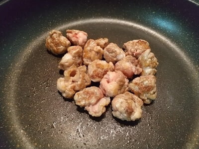 フライパンで丸めた豚肉を焼く写真