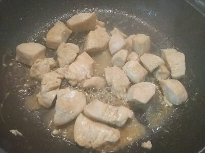 フライパンで鶏むね肉を両面焼き色が付くまで焼いて調味料を入れてからませた写真