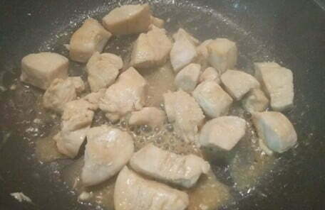 フライパンで鶏むね肉を両面焼き色が付くまで焼いて調味料を入れてからませた写真