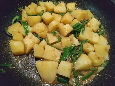 フライパンでピーマンを炒めてじゃがいもと調味料も入れて炒める写真