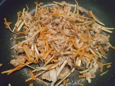 フライパンで豚肉を焼きにんじん、ごぼうも入れ調味料も入れて煮詰めた写真